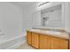 Bathroom featuring double sinks, wood cabinets, bathtub, and a large mirror at 7219 Rafanelli Ct, Orlando, FL 32818