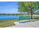 Scenic lake view with a green bench under a large tree on a sunny day at 7219 Rafanelli Ct, Orlando, FL 32818