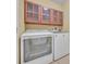 Laundry room with front load washer and dryer and wooden cabinets with frosted glass at 7219 Rafanelli Ct, Orlando, FL 32818