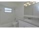 Bathroom with white vanity, granite countertop, tub with white tile, and updated fixtures at 7717 Boreas Dr, Orlando, FL 32822