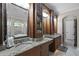 Bathroom vanity featuring dual sinks, granite counters and custom cabinetry with glass display shelving at 8713 Shimmering Pine Pl, Sanford, FL 32771