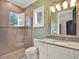 Serene bathroom with light green wallpaper, granite counters, and a tiled shower and tub at 9372 Thurloe Pl, Orlando, FL 32827