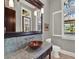 Bathroom featuring a unique vessel sink, a stone-tile backsplash, and a view to the backyard at 9372 Thurloe Pl, Orlando, FL 32827