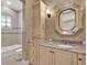 Neutral toned bathroom with a unique mirror, granite counters, and built in linen storage at 9372 Thurloe Pl, Orlando, FL 32827