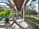 A long covered patio with classic columns, a ceiling fan, and view of the pool, spa, and lush landscaping at 9372 Thurloe Pl, Orlando, FL 32827