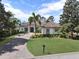 Elegant one-story home featuring a tile roof, lush landscaping, and a brick driveway at 9372 Thurloe Pl, Orlando, FL 32827