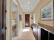 Inviting hallway featuring travertine flooring, a dark wood cabinet and interior access to other rooms in the home at 9372 Thurloe Pl, Orlando, FL 32827