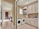 Well-appointed laundry room boasts ample cabinet space, modern appliances and travertine tile at 9372 Thurloe Pl, Orlando, FL 32827