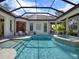 Beautiful pool with spa and waterfall feature, surrounded by lush landscaping and a screened enclosure at 9372 Thurloe Pl, Orlando, FL 32827