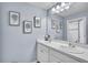 Bright bathroom offers double sinks, white cabinetry, and decorative artwork on the light blue walls at 9401 La Salle St, Groveland, FL 34736