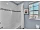 Modern bathroom showcases tiled shower with decorative band, curtain, and window with blinds at 9401 La Salle St, Groveland, FL 34736