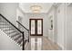 Grand foyer with elegant double doors, a stunning chandelier, and staircase with black railings at 1185 Cypress Loft Pl, Lake Mary, FL 32746