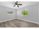 Neutral bedroom features wood-look flooring, ceiling fan, and two sunny windows at 1259 Freeport Dr, Deltona, FL 32725