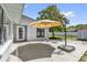 View of the rear outdoor patio with sun umbrella and a white door and window on the light gray home at 1259 Freeport Dr, Deltona, FL 32725