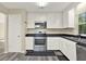 Well-lit kitchen featuring stainless steel appliances, white cabinets, black countertops, and wood-look flooring at 2202 Clubside Dr # 2202, Longwood, FL 32779