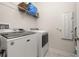 Modern laundry room features a white washer and dryer with a wire shelf for storage at 430 Brunswick Dr, Davenport, FL 33837