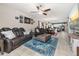 Open-concept living room view showcasing leather sofas, ceiling fan, and access to the dining area and kitchen at 430 Brunswick Dr, Davenport, FL 33837