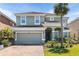 Beautiful two-story home with a grey two-car garage door, lush landscaping, and a red-tiled roof at 4416 Shiva Loop, Kissimmee, FL 34746