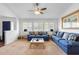 Bright living room with plush blue couches, a ceiling fan, and natural light streaming through the windows at 516 Donaldson Dr, Debary, FL 32713