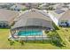 Aerial view of the backyard featuring a screened pool, lush green lawn, and meticulously manicured landscaping at 588 Hitch Loop, St Cloud, FL 34772