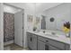 Clean bathroom with a double vanity, gray cabinets, white countertops, and a shower with patterned curtain at 588 Hitch Loop, St Cloud, FL 34772