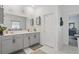 Well-lit bathroom showcases a double vanity with gray cabinets, a large mirror, and white tile flooring at 588 Hitch Loop, St Cloud, FL 34772