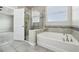 Bathroom featuring a bathtub and glass-enclosed shower, with tiled walls and floors at 8433 Corkfield Ave, Orlando, FL 32832
