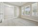 Bright, neutral room with carpet, natural light from three windows, and french doors leading to another room at 8433 Corkfield Ave, Orlando, FL 32832
