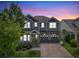 Charming two-story home exterior with lush landscaping, brick driveway, and a covered front porch at dusk at 8433 Corkfield Ave, Orlando, FL 32832