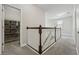Upstairs hallway with white railing, neutral walls, carpet floors, and a wire rack shelving storage unit at 8433 Corkfield Ave, Orlando, FL 32832