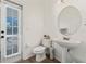 Small powder room featuring pedestal sink, rounded mirror, and access to outdoor patio at 848 Jadestone Cir, Orlando, FL 32828