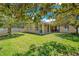 A backyard view featuring a covered patio, green lawn, mature trees and a white picket fence at 10027 Hart Branch Cir, Orlando, FL 32832