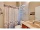 Bathroom with a shower featuring a decorative curtain, floating shelves, and a wooden vanity at 10027 Hart Branch Cir, Orlando, FL 32832