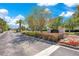 A community entrance is adorned with colorful flowers, manicured hedges, and a stone sign under a sunny sky at 10027 Hart Branch Cir, Orlando, FL 32832