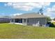 Rear exterior view of home featuring a screened-in porch and green backyard at 10367 Sw 45Th Ave, Ocala, FL 34476