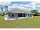 Rear exterior view of home featuring a screened-in porch and green backyard at 10367 Sw 45Th Ave, Ocala, FL 34476