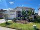 Inviting single-story home with a well-manicured lawn, mulch beds, and mature tropical plants at 1352 Royal Saint George Dr, Orlando, FL 32828