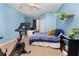 A blue bedroom with a Peloton, a bed, and a desk. Perfect for exercise and relaxation at 14316 Fredricksburg Dr # 507, Orlando, FL 32837