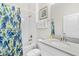 Bright bathroom featuring a shower with a floral curtain, white sink, and a decorative print on the wall at 1551 Flange Dr, Davenport, FL 33896