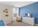 Comfortable bedroom with blue accent wall, white dresser, chair, TV and an artwork piece at 1551 Flange Dr, Davenport, FL 33896