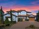 Elegant Mediterranean-style home with a brick driveway and manicured landscaping at sunset at 15681 Panther Lake Dr, Winter Garden, FL 34787