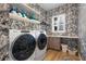 Convenient laundry room with a modern washer and dryer, shelving, and leaf-themed wallpaper at 15681 Panther Lake Dr, Winter Garden, FL 34787