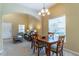 Bright dining area with a wood table and chairs beneath a decorative chandelier, adjacent to a cozy living space at 16241 Old Ash Loop, Orlando, FL 32828