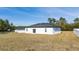 A home with white stucco and a black roof has a sliding door that opens to a spacious backyard at 17236 Sw 44Th Cir, Ocala, FL 34473