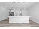 A modern, open kitchen features an island with pendant lighting, stainless appliances, and white cabinetry at 17236 Sw 44Th Cir, Ocala, FL 34473
