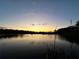 Scenic lake view at sunset reflects a golden glow on the calm water and surrounding trees at 278 Silverstone Dr, Orange City, FL 32763