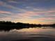 The sun rises in the distance as streaks of pinks and oranges reflect off the calm lake at 278 Silverstone Dr, Orange City, FL 32763