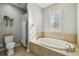 Bright bathroom showcasing a soaking tub, shower with white shower curtain, and a window with shutters at 2827 Upper Park Road, Orlando, FL 32814