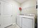 Bright laundry room featuring a white washer and dryer and storage shelf at 2861 Black Birch Dr, Ocoee, FL 34761