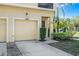 A garage door and front door, accented by a light fixture and tropical landscaping at 2898 Oakwater Dr # 2898, Kissimmee, FL 34747